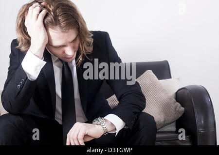 Mann trägt Anzug Überprüfung Uhr für Zeit mit einer Hand am Kopf suchen gestresst Stockfoto