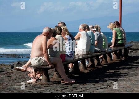 Playa de Las Americas, Spanien, Senioren sonnen sich auf einer Bank direkt am Meer auf Teneriffa Stockfoto