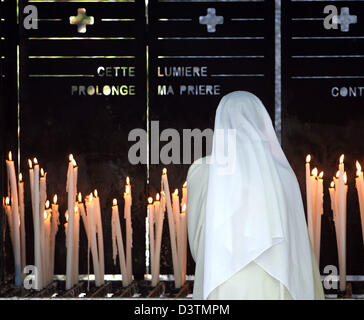 (Dpa-Datei) - eine Nonne mit einem weißen Schleier steht vor einer Nische mit brennenden Kerzen in den Wallfahrtsort Lourdes, Frankreich, 8. September 2006. Am 11. Februar 1858 14-jährigen Bernadette Soubirous hatte Visionen von der Jungfrau Maria in der Grotte Massabielle in der Nähe des Flusses Gave du Pau wiederholt. Während einer dieser Visionen entdeckt Berrnadette die Grotte, deren Wasser als c gilt Stockfoto