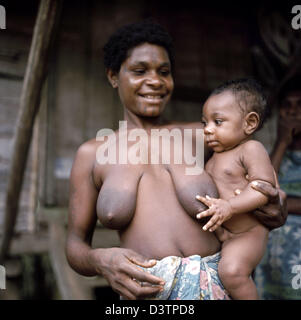 Das undatierte Bild zeigt eine lächelnde Papua Mutter hält ihr Kind auf dem Arm in Papua-Neu-Guinea. Die Bevölkerung von Papua-Neu-Guinea, bestehend hauptsächlich aus Papua, ist sehr vielfältig. Die Papua sind Jäger, Sammler und Nutzpflanzen wie Yam, Maniok und Bananen zu kultivieren. Pfeil und Bogen sind noch gebräuchlich, wie Steinbeile und Stöcke zu graben. Schweine sind sehr wichtig als domestiziertes Tier Stockfoto