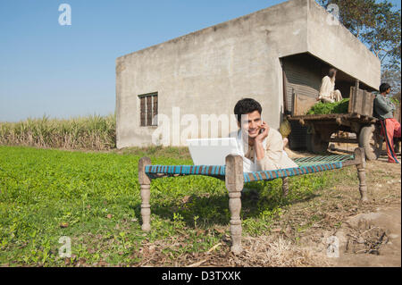 Landwirt mit einem Laptop und telefonieren mit einem Handy im Feld, Sonipat, Haryana, Indien Stockfoto