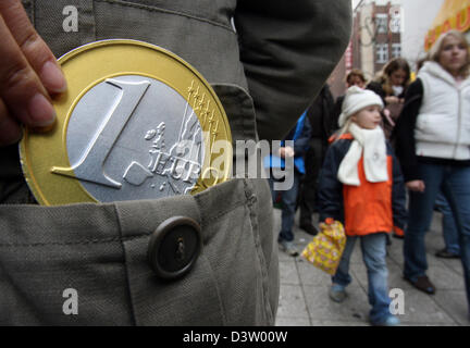 (Dpa-Dateien) - das symbolische Foto zeigt eine überdimensionale-Euro-Münze in der Tasche eines Verbrauchers in Frankfurt Main, Deutschland, Samstag, 2. Dezember 2006. Einzelhändler begnügten sich mit ihren Umsatz nach dem ersten Adventswochenende mit längeren Öffnungszeiten. Foto: Boris Roessler Stockfoto