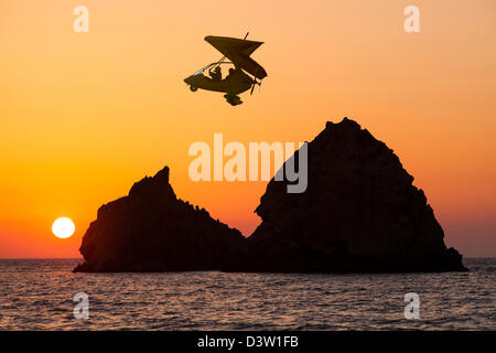 Sonnenuntergang über felsigen Inseln vor Myrina auf Lemnos, Griechenland, mit einem motorisierten Gleitschirm. Stockfoto