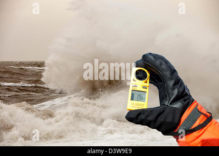 Gale force Winde und Wellen, die Misshandlung der Küstenschutz in Harrington, Workington, Cumbria, England, mit einem anemometer Stockfoto