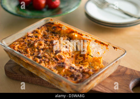 Pasta mit Hackfleisch, Käse-Sauce und Tomaten in ein Glas Auflaufform auf einem Holzbrett. Stockfoto