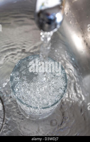 Wasser läuft in einem Glas, aus einem Wasserhahn in der Küche. Stockfoto