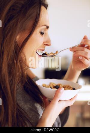 Seitenansicht einer gesunden Frau Lächeln während des Essens ihr Getreide Stockfoto