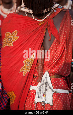 Am Ende ein junger Maasai Mann bei einer Hochzeitsfeier. Er trägt traditionelle rote Shuka, geflochtene Haare mit Perlen und Gürtel. Stockfoto