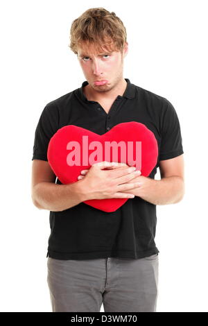 Unglückliche Liebe. Lustiges Bild von traurig gebrochenes Herz Valentinstag Mann hält rotes Herz isoliert auf weißem Hintergrund Stockfoto