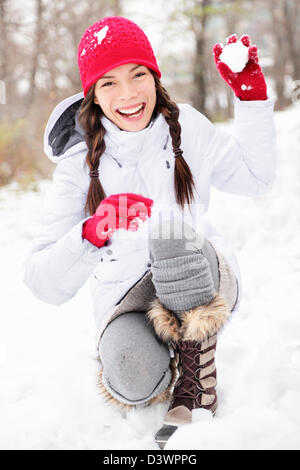 Schöne freudige asiatischen kaukasischen Frau spielt im Schnee Kamera Spaß außerhalb auf schneit Wintertag Schneeball bewerfen Stockfoto