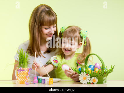 Mutter und Kind Mädchen malen Ostereier auf grünem Hintergrund Stockfoto