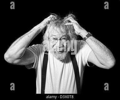 Monochrom Senior mit einem wahnsinnigen Blick auf seinem Gesicht und Händen packte seine Haare isoliert auf schwarz Stockfoto