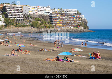 Menschen, die zum Sonnenbaden am sandigen Strand von San Augustin, Gran Canaria Stockfoto