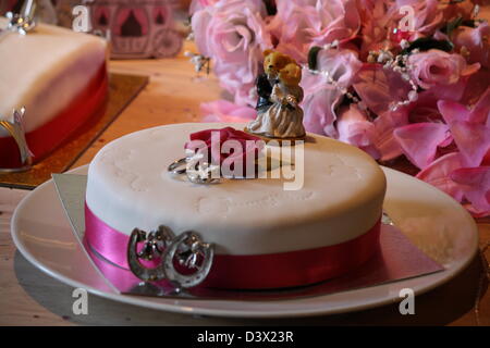 Hochzeitstorte mit zwei trägt es mit einem Blumenstrauß hinter. Stockfoto