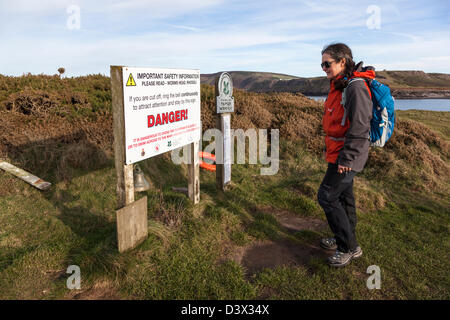 Walker lesen Gefahrenzeichen, abgeschnitten von der Flut auf Würmer Kopf, Rhossili, Gower, Wales, UK Stockfoto