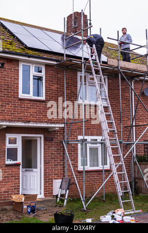 Zwei Männer, die Montage von Sonnenkollektoren auf dem Dach eines Hauses in Großbritannien Stockfoto