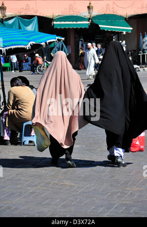 Zwei marokkanische Frauen tragen Abaya oder traditionelle Kleidung für arabische Frauen zu Fuß über den Jemaa El Fna Platz in Marrakesch Stockfoto