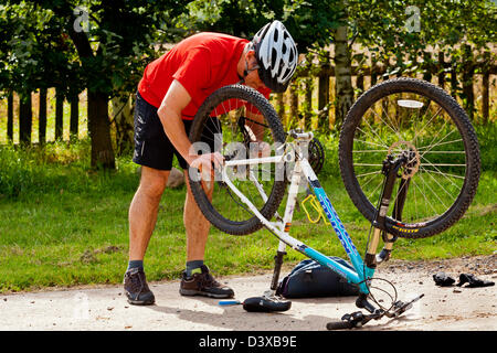 Mann in wechselnden Hinterrad rotes Hemd und Reparatur Punktion mit Mountainbike Stockfoto