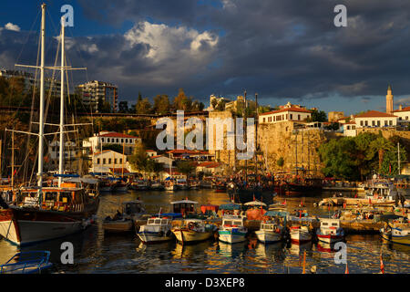 Große Schiffe und Boote vertäut im Hafen von Antalya Türkei mit römischen Mauer Befestigung bei Sonnenuntergang Stockfoto