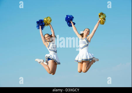 Kaukasische Cheerleader springen in der Luft Stockfoto