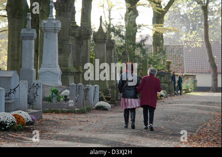 Zwei Damen gehen durch den Friedhof die Gräber ihrer Angehörigen für Allerheiligen vorzubereiten. Stockfoto