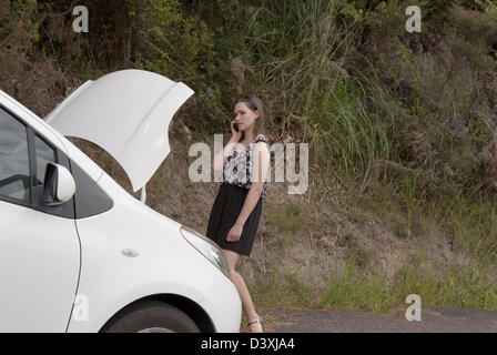 Eine junge Frau steht auf ihrem Handy neben ihr Auto zerlegt sprechen. Stockfoto