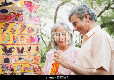 Älteres paar kaufen Eis von einem Lebensmittel stall, Lodi Gardens, New Delhi, Indien Stockfoto