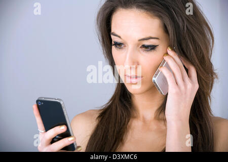 Junge Frau mit zwei iPhones. Stockfoto