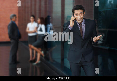 Geschäftsmann, telefonieren mit einem Handy mit ihren Kollegen im Hintergrund Stockfoto