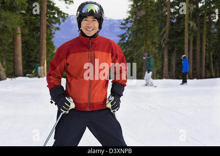 Chinesischer Mann tragen Skiausrüstung im Schnee Stockfoto