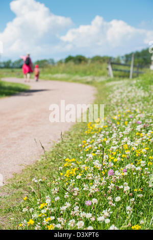 Erwachsene Frau und Kind gemeinsam auf Trek, hinunter ländliche Schotterstraße an einem warmen Sommertag. Stockfoto