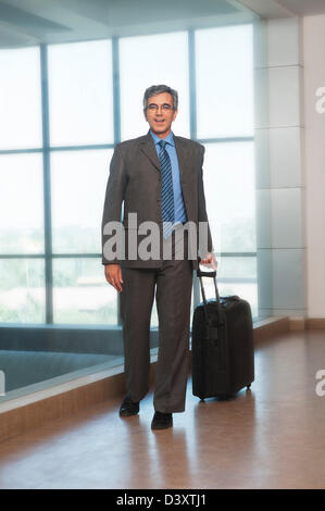 Geschäftsmann eine Trolley-Tasche ziehen und lächelnd Stockfoto