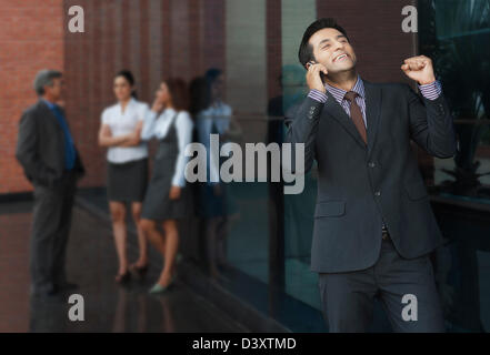 Geschäftsmann, telefonieren mit einem Handy mit ihren Kollegen im Hintergrund Stockfoto