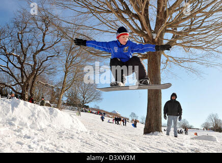 Junge springt auf ein Snowboard in CT USA. New England Winter. Stockfoto