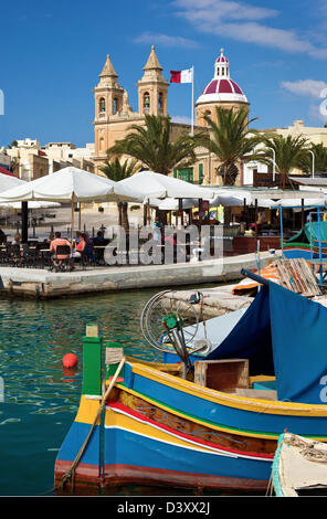 Café im Freien und traditionellen maltesischen Fischerboot. Marsaxlokk, Malta. Stockfoto