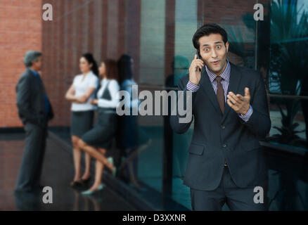 Geschäftsmann, telefonieren mit einem Handy mit ihren Kollegen im Hintergrund Stockfoto