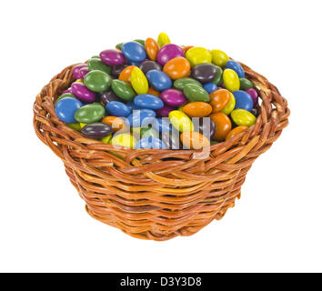 Ein kleiner Korb gefüllt mit bunt gestrichenen Schokoladenstücke. Stockfoto