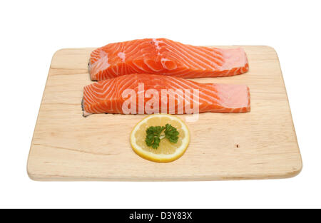 Zwei rohen Lachs-Steaks mit einer Scheibe Zitrone und Petersilie auf einem Holzbrett isoliert gegen weiß Stockfoto