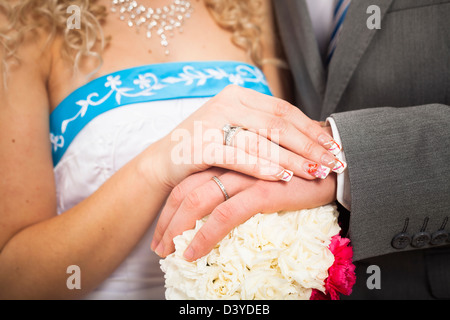 Detail der Hände der Braut und des Bräutigams mit Ringen und Blume Hochzeit. Stockfoto