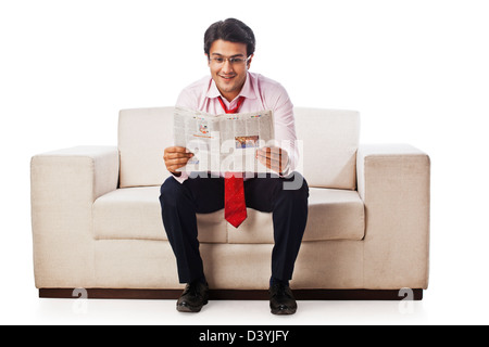 Geschäftsmann auf einer Couch sitzen und eine Zeitung lesen Stockfoto