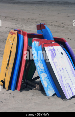 Body-Boards oder Boogie Boards gestapelt auf dem Sand des Strandes am Pazifischen Ozean in Tonsupa, Ecuador Stockfoto