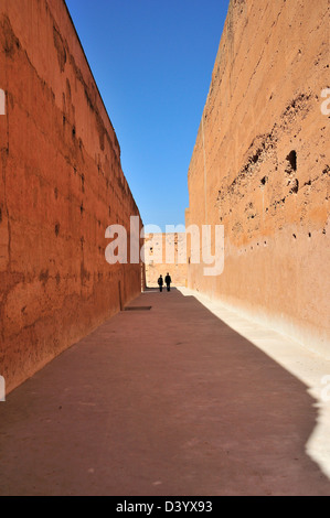 Paar in der Ferne zu Fuß zwischen zwei alten rosa farbenen hohe Mauern im Palazzo El Badii, Marrakesch, Marokko Stockfoto