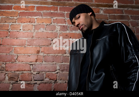 Harter Kerl gekleidet in schwarz in der Nähe einer Mauer. Stockfoto