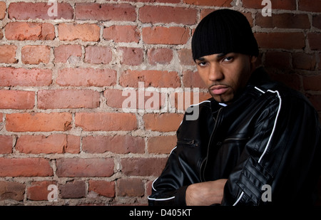 Dunkle und düstere Mann in schwarz gekleidet, an die Wand gelehnt. Stockfoto