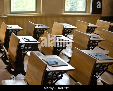 Alten Klassenraum mit antiken Stühle und Tische mit kleinen Tafeln auf dem Schreibtisch für das schreiben. Stockfoto
