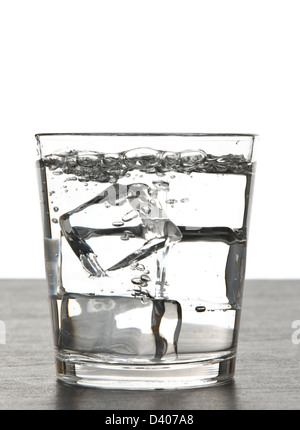 Glas Wasser über Eiswürfel mit weißem Hintergrund. Stockfoto