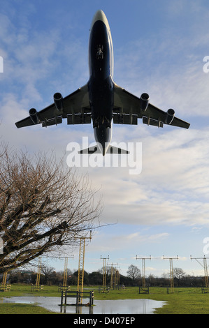 British Airways Boeing 747 Jumbo Jet landet am London Heathrow Airport tief über den Landungslichtern und überfluteten Feldern Stockfoto