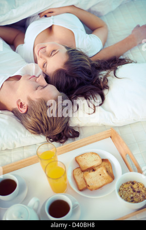 Glückliche Frau und ihr Mann am Bett morgens entspannen Stockfoto