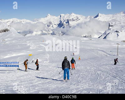 Skifahrer, die blau auf Les Grandes Platieres im Skigebiet Le Grand Massif mit schneebedeckten Bergen in den französischen Alpen laufen. Flaine, Frankreich Stockfoto