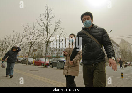 Ein Paar mit Gesichtsmasken geht eine Straße in der chinesischen Hauptstadt hinunter, die von Smog umhüllt ist. Wann immer die Nordwinde stoppen, verbinden sich die umweltschädlichen Kohlekraftwerke, die Verbrennung von Getreide und die Abgase des Verkehrs, was zu gefährlicher Luftverschmutzung führt, die im Luftqualitätsindex häufig über 500 liegt, wie hier im Chaoyang-Bezirk von Bejiing, China, PRC, zu sehen ist. © Time-Snaps Stockfoto